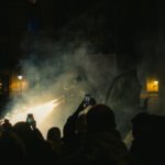 Performance Gap - A crowd of people standing in front of a building with smoke coming out of it