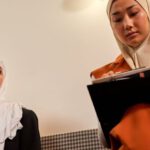 Low-Cost Laptops - Two Women at Work in Hijabs Sitting in Office and Working on Laptops
