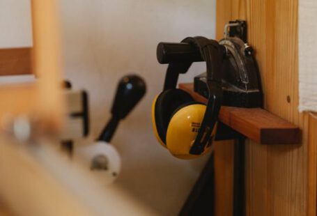 Noise-Canceling Headphones - Yellow noise cancelling headphones for carpentry work hanging on timber shelf in workshop